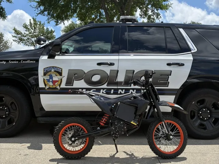Electric dirt bike photographed outdoors near a service vehicle